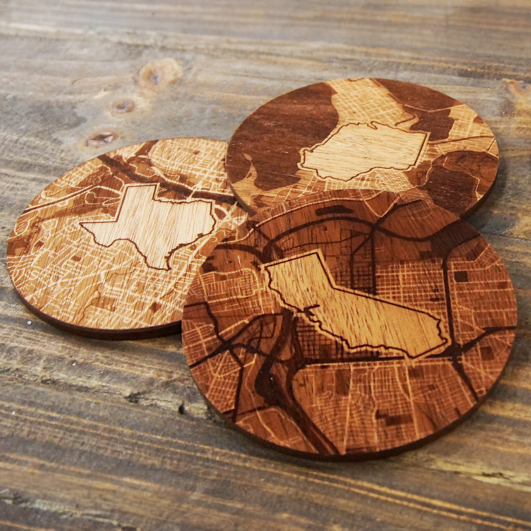 Wooden coasters featuring intricately engraved state maps and city street designs.